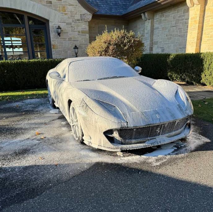 A car is covered in foam in front of a house.