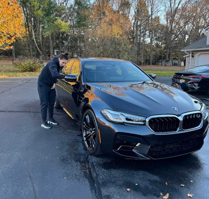 A man is washing a black bmw in a driveway