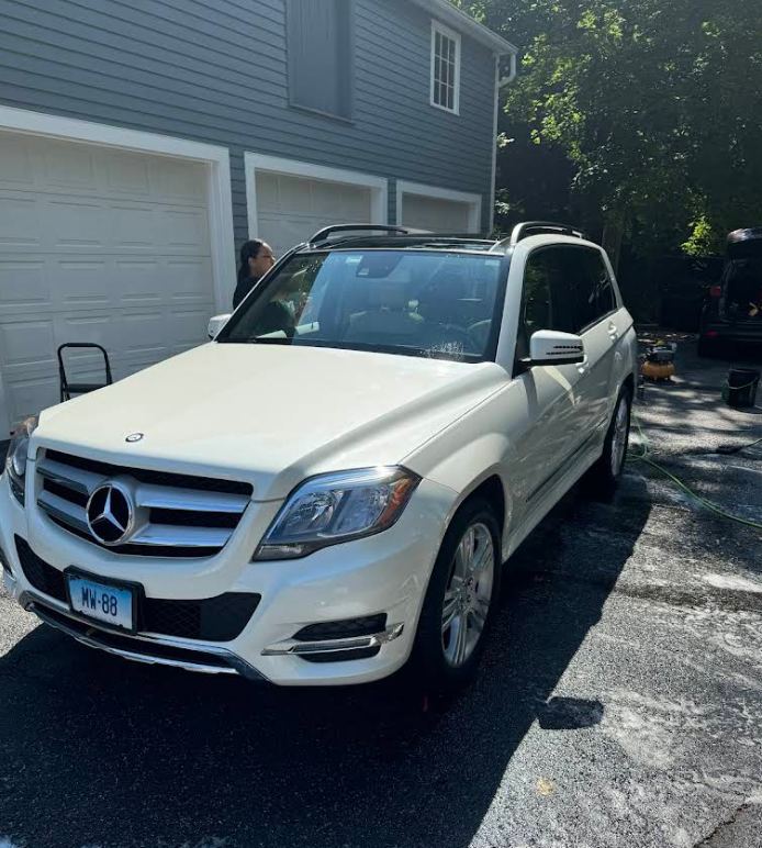 A white mercedes benz suv is parked in front of a garage