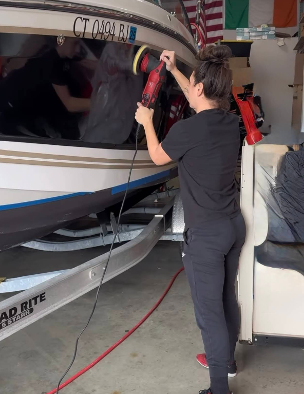 A man is polishing a boat with a ct license plate