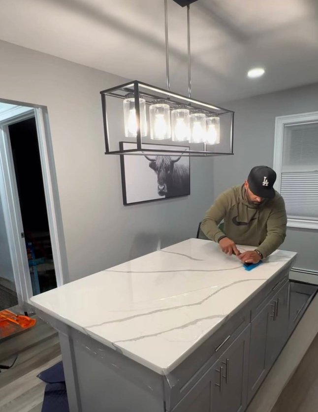 A man is working on a white counter top in a kitchen.