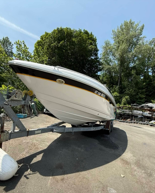A white boat is parked on a trailer in a parking lot.