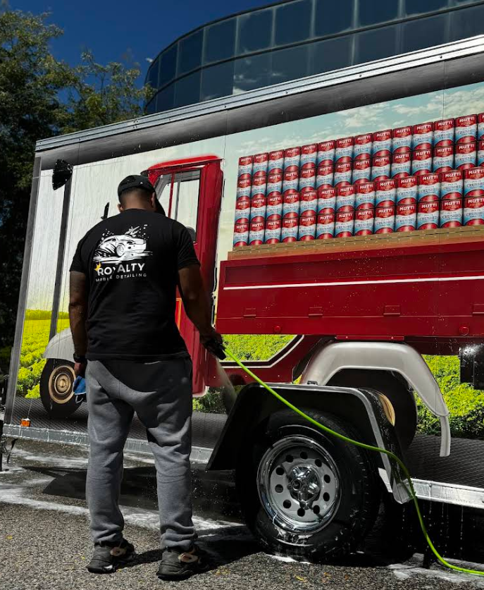 A man in a black shirt is standing next to a can truck