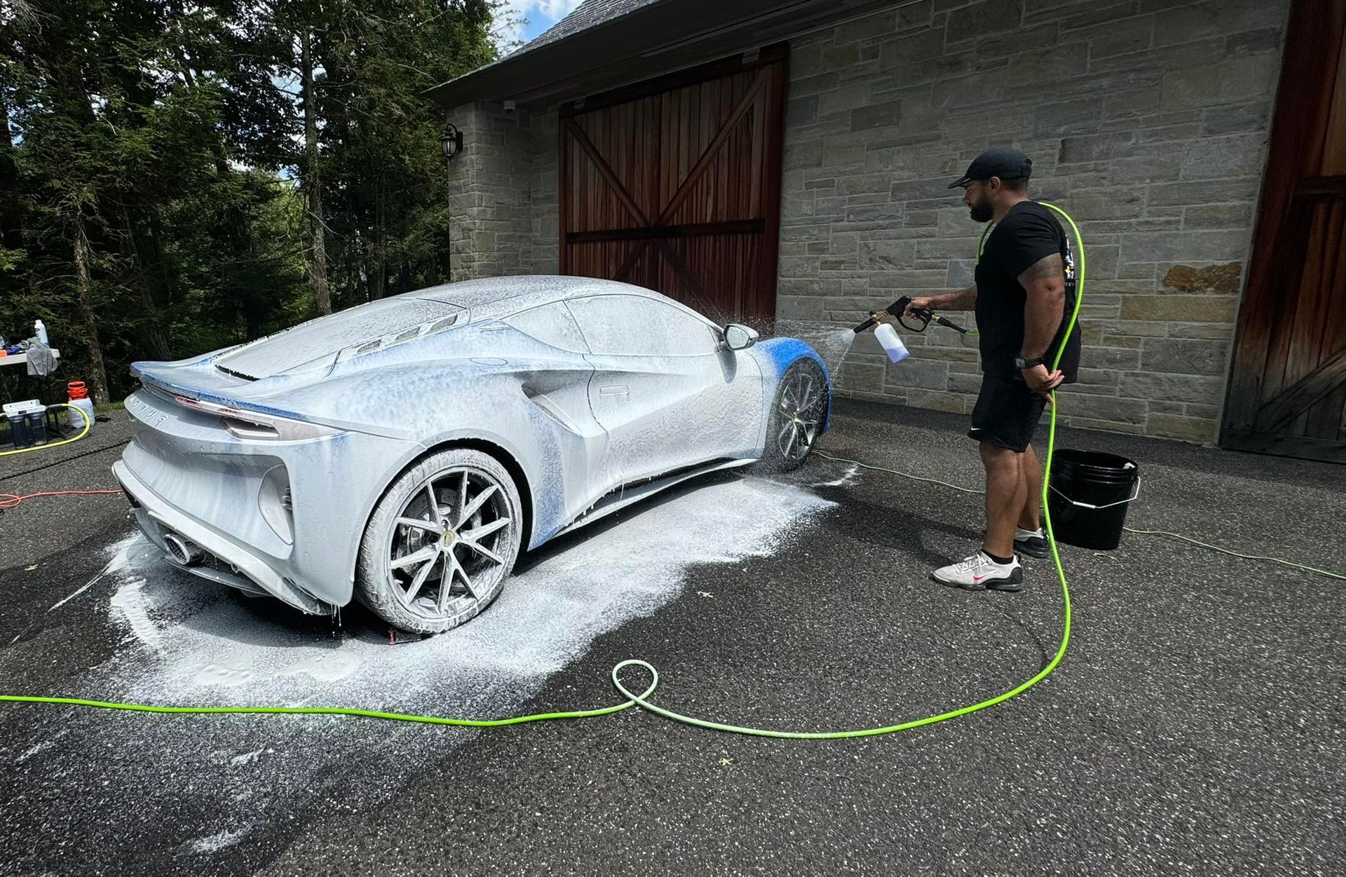 A man is washing a white sports car with foam.