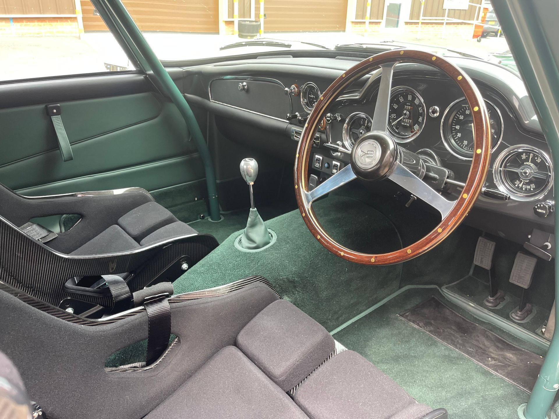The interior of a green car with a wooden steering wheel