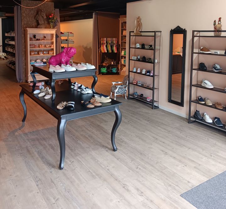 Een winkel met veel schoenen op planken en een tafel