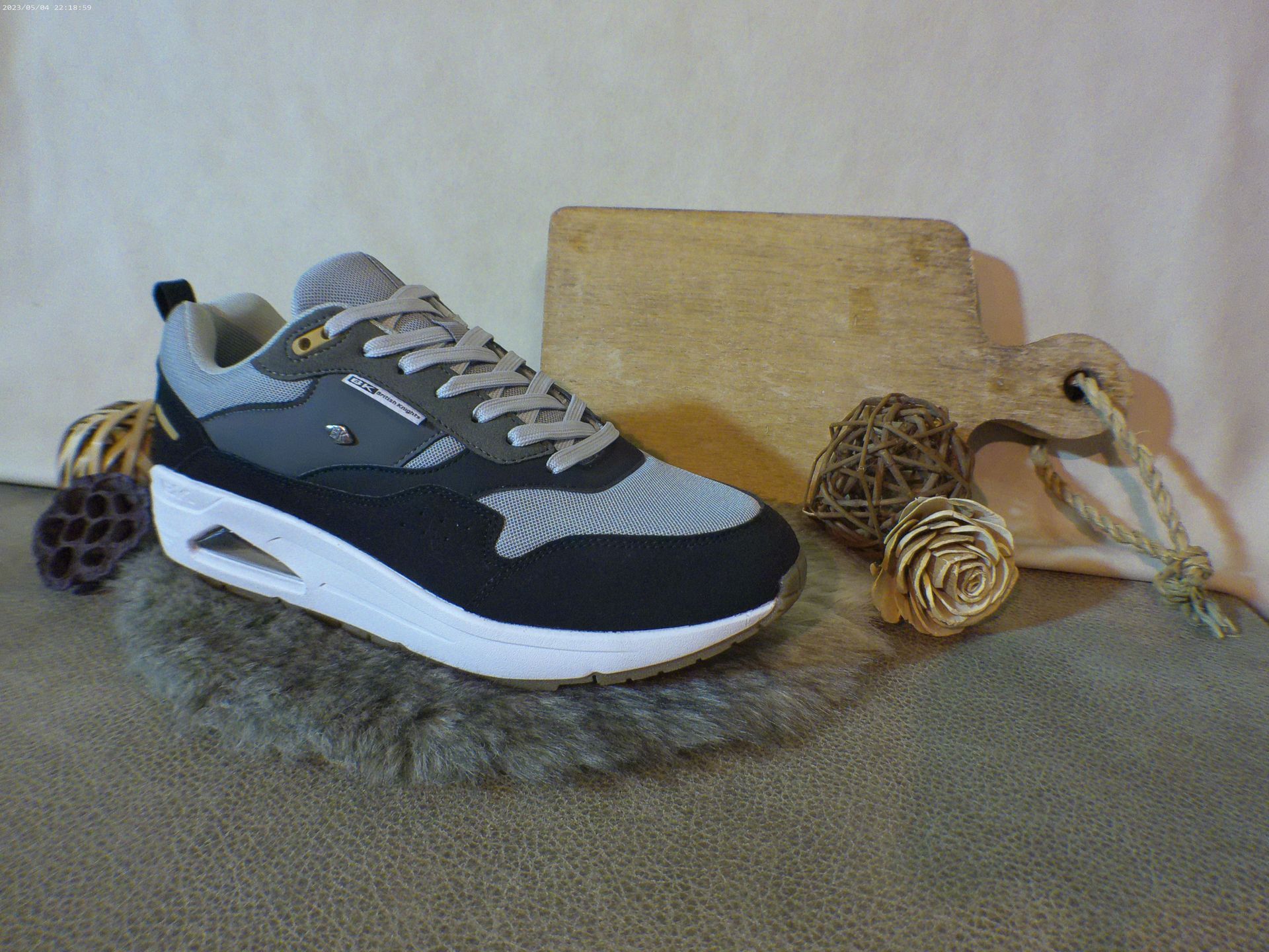 Een paar zwart-grijze sneakers liggen op een tapijt.