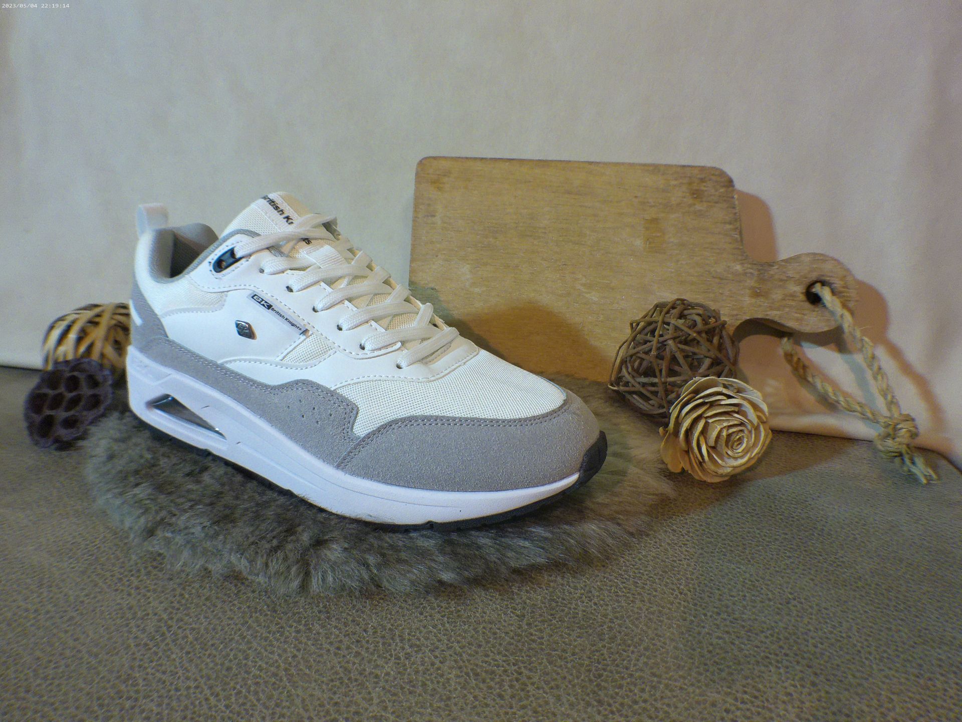 Een paar wit-grijze sneakers liggen op een tapijt.