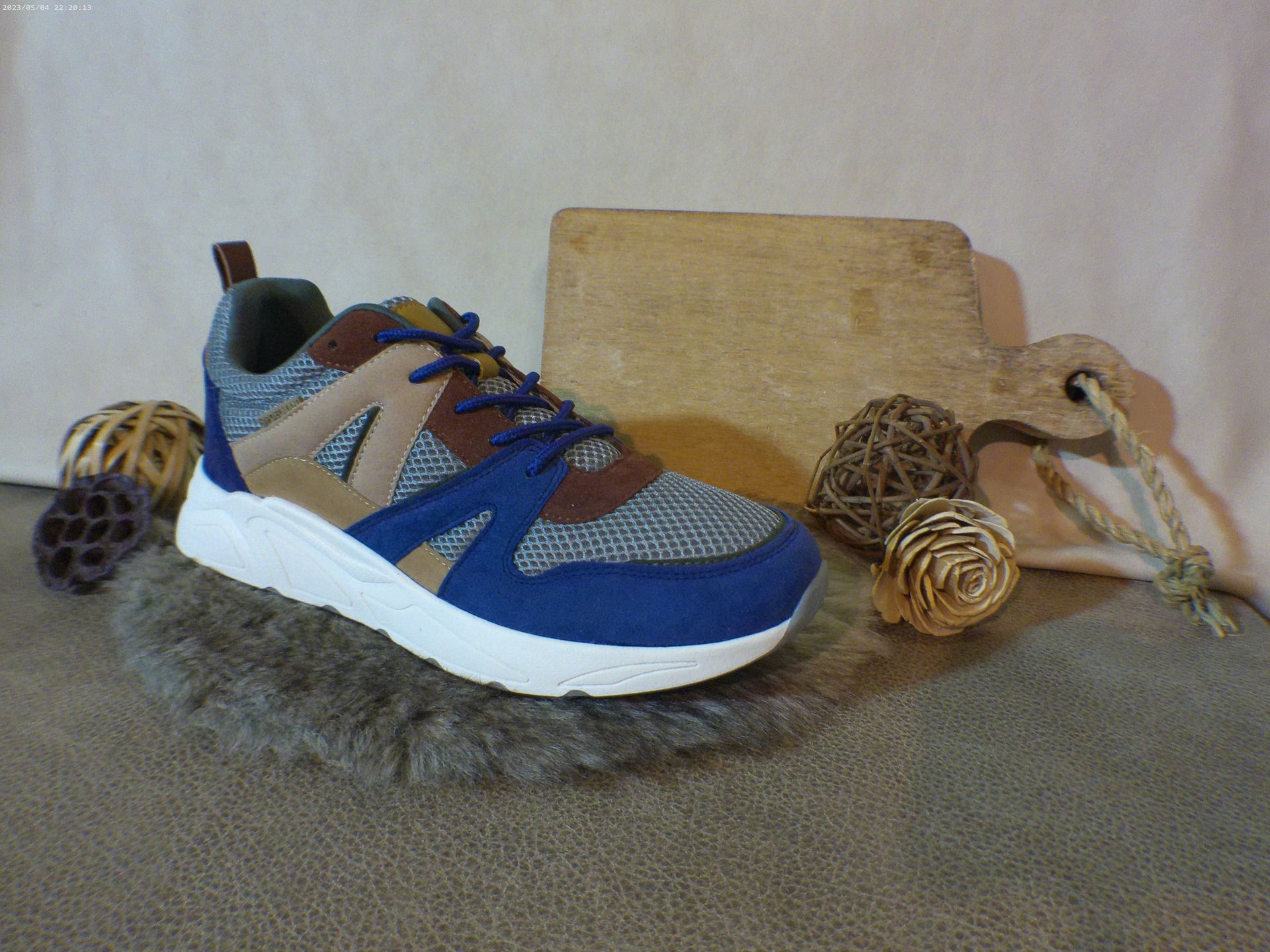 Een paar blauwe en bruine sneakers liggen op een tapijt.