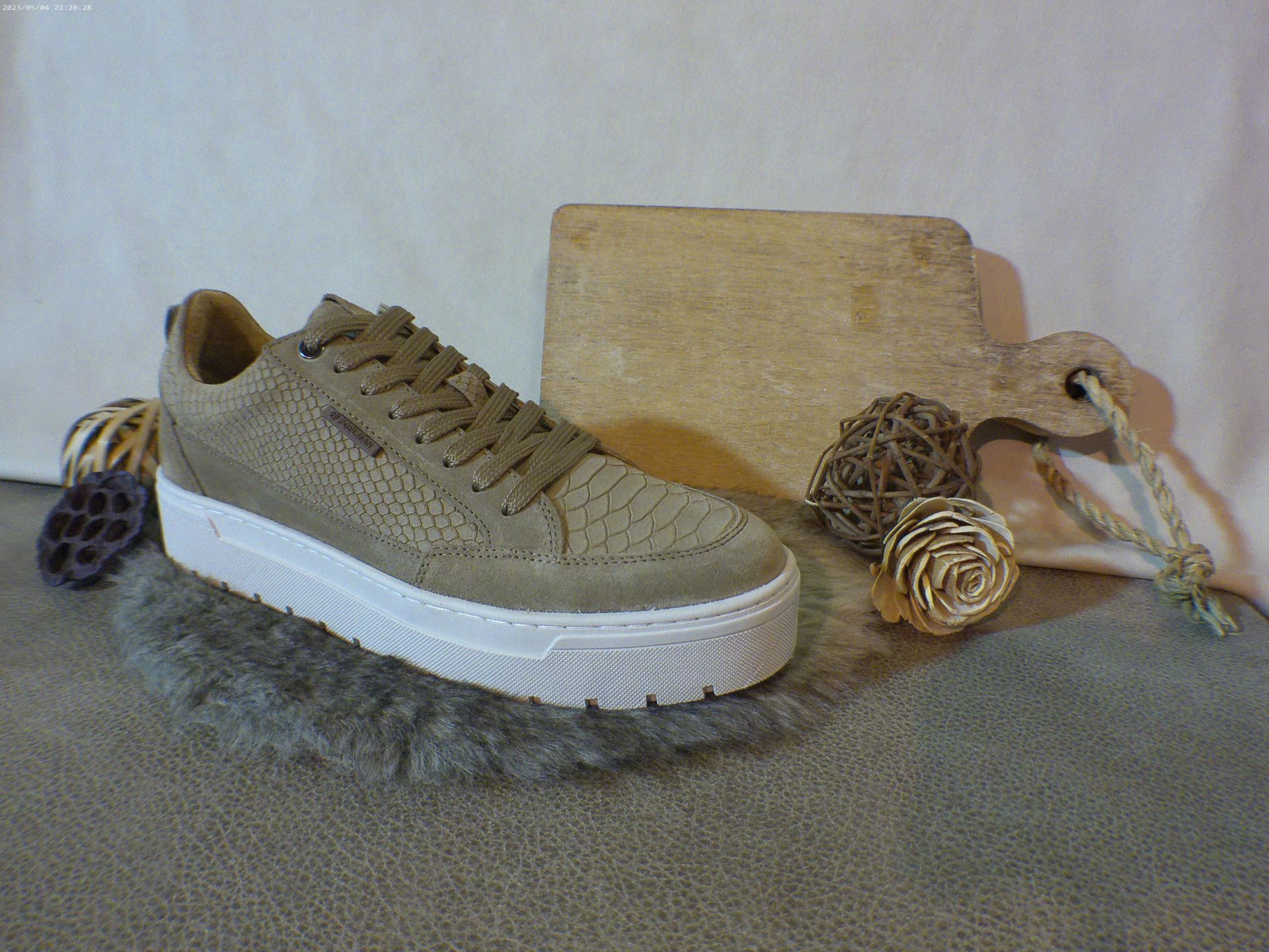 Een paar sneakers liggen op het tapijt naast een handtas.