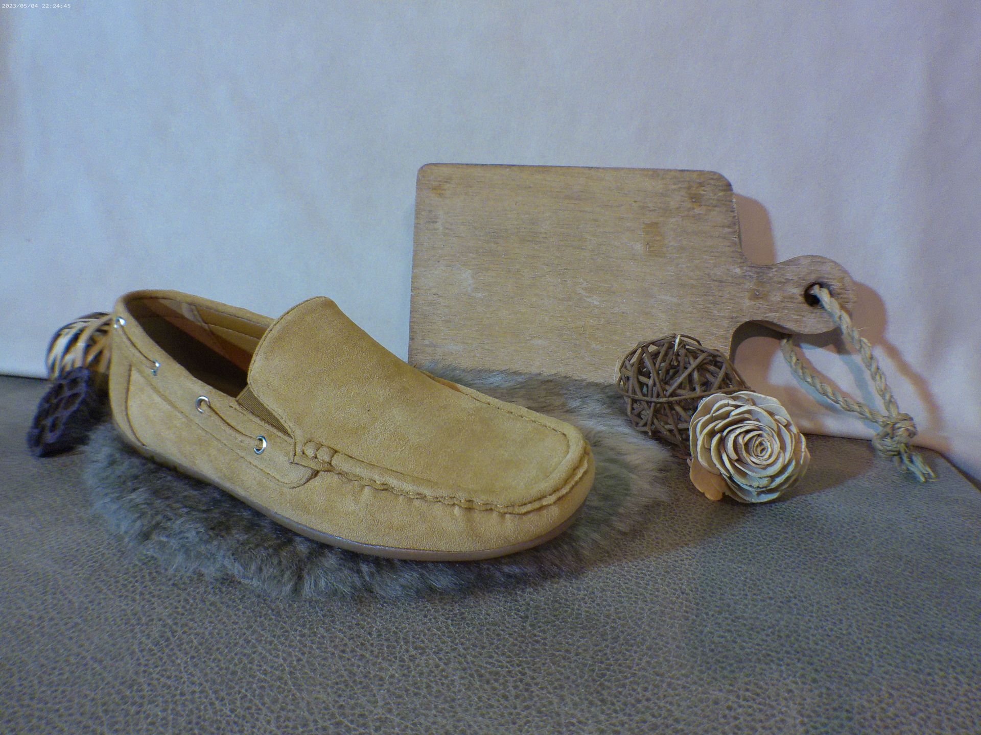 Een paar loafers liggen op een tapijt naast een houten snijplank.