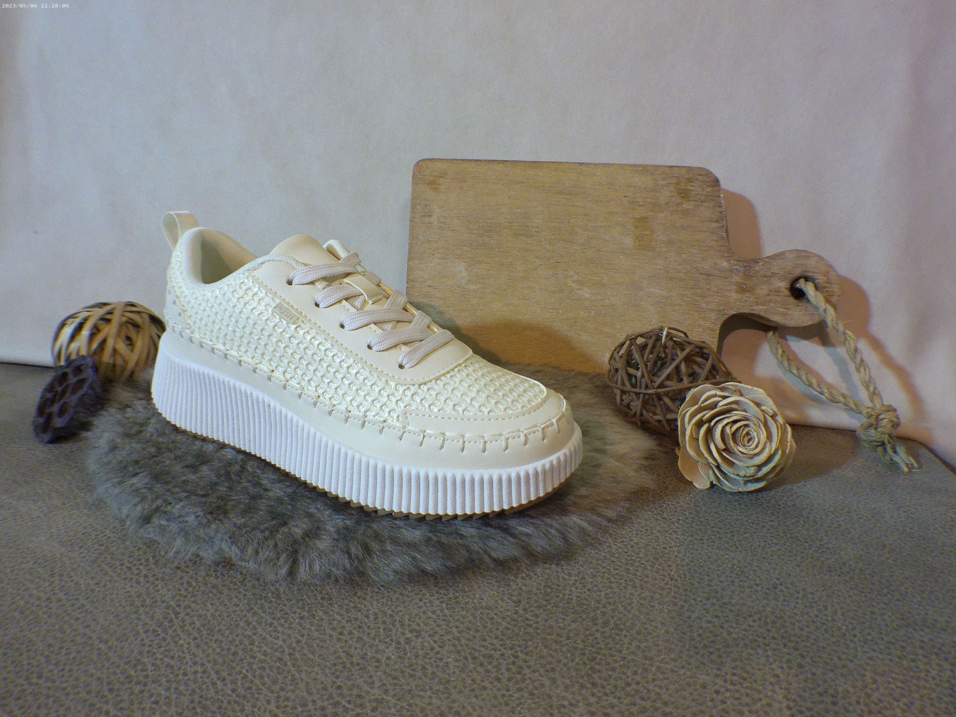Een paar witte sneakers liggen op een tapijt naast een snijplank.