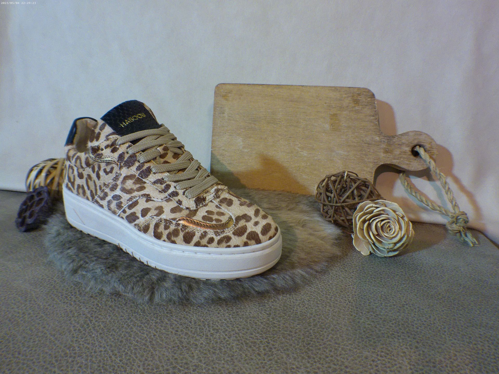 Een paar sneakers met luipaardprint liggen op de bank naast een snijplank.