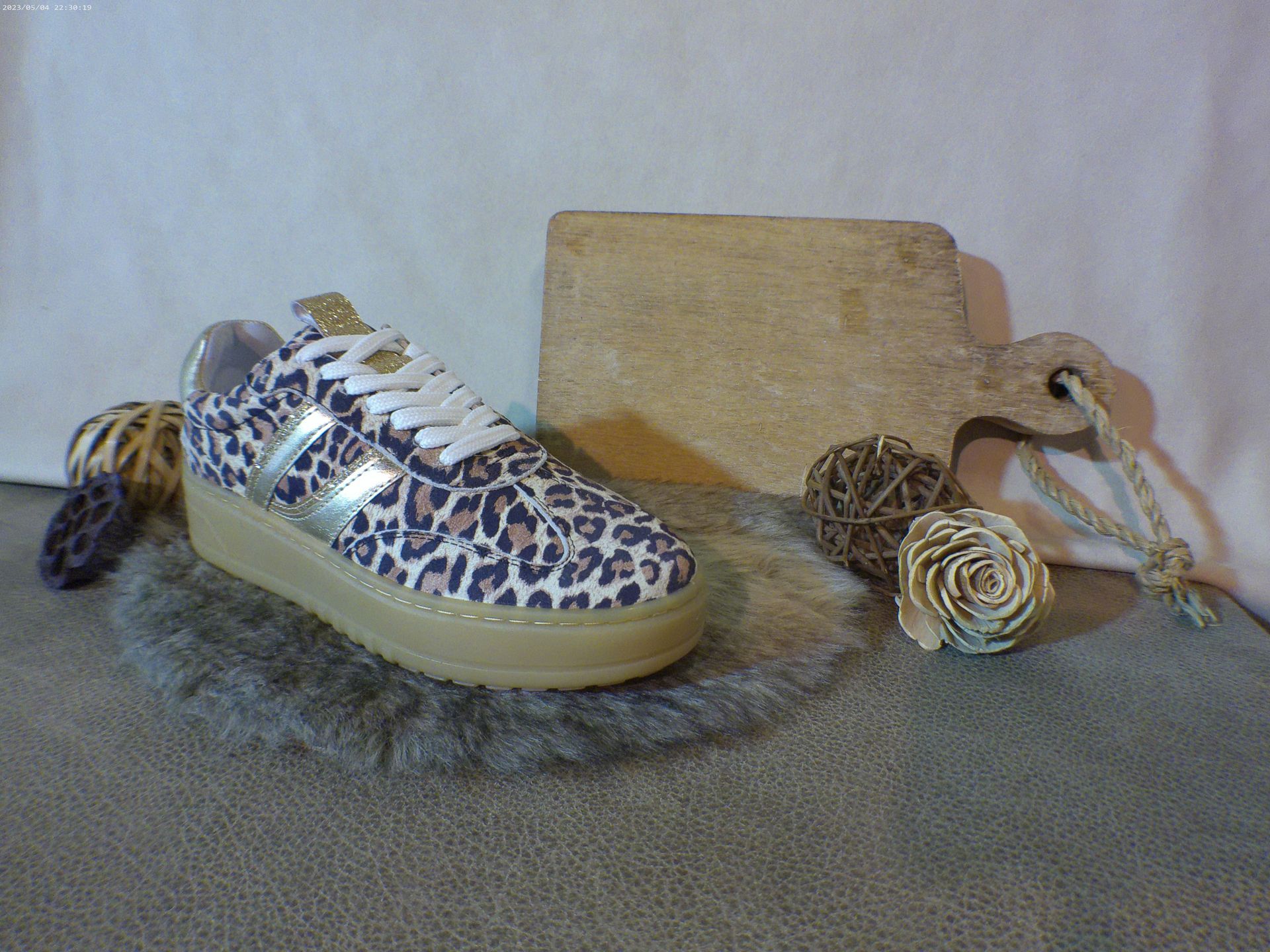 Een paar sneakers met luipaardprint liggen op een tapijt.