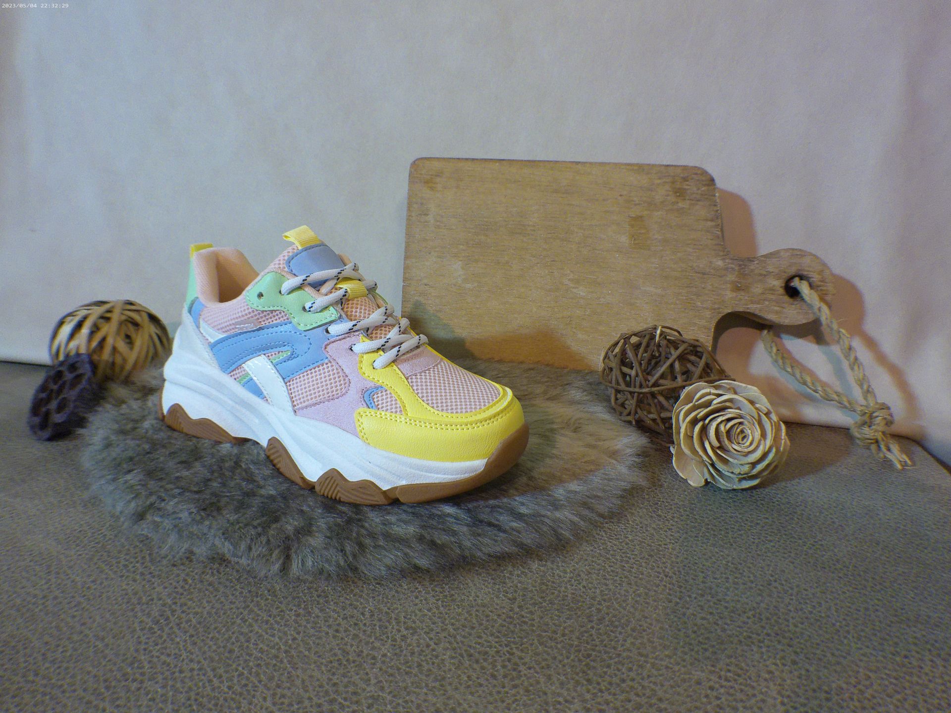 Een paar kleurrijke sneakers liggen op een tapijt naast een snijplank.