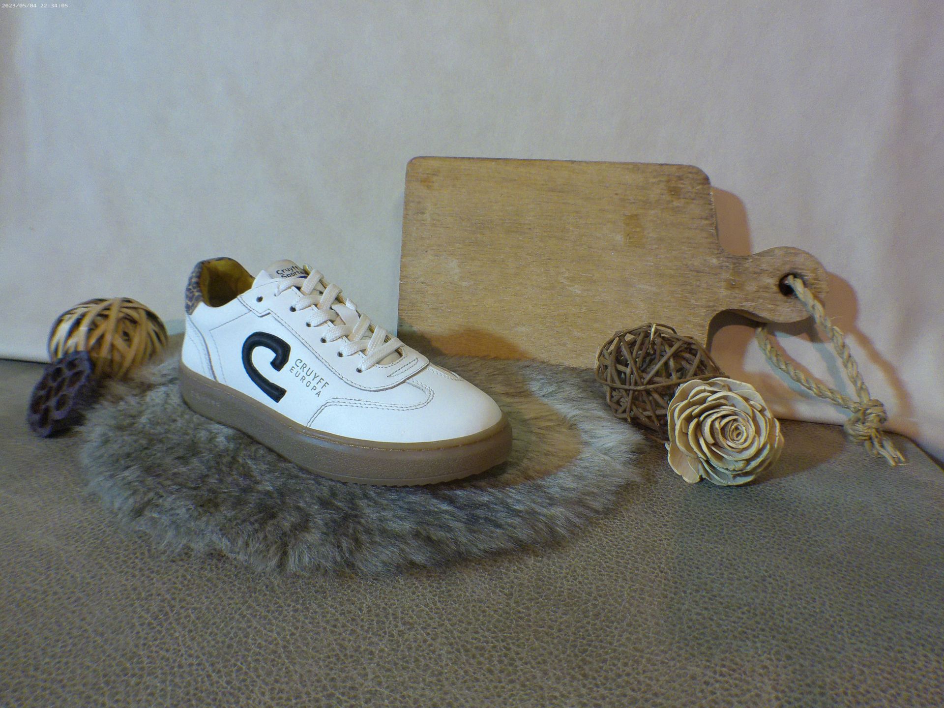 Een paar witte sneakers met een zwarte c aan de zijkant liggen op een bontkleed.