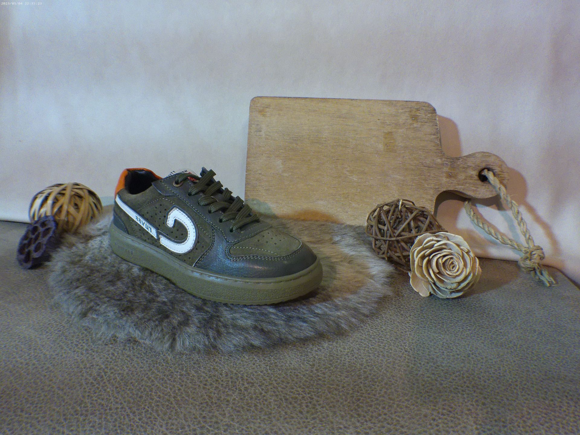 Een paar groene sneakers liggen op een tapijt naast een snijplank.