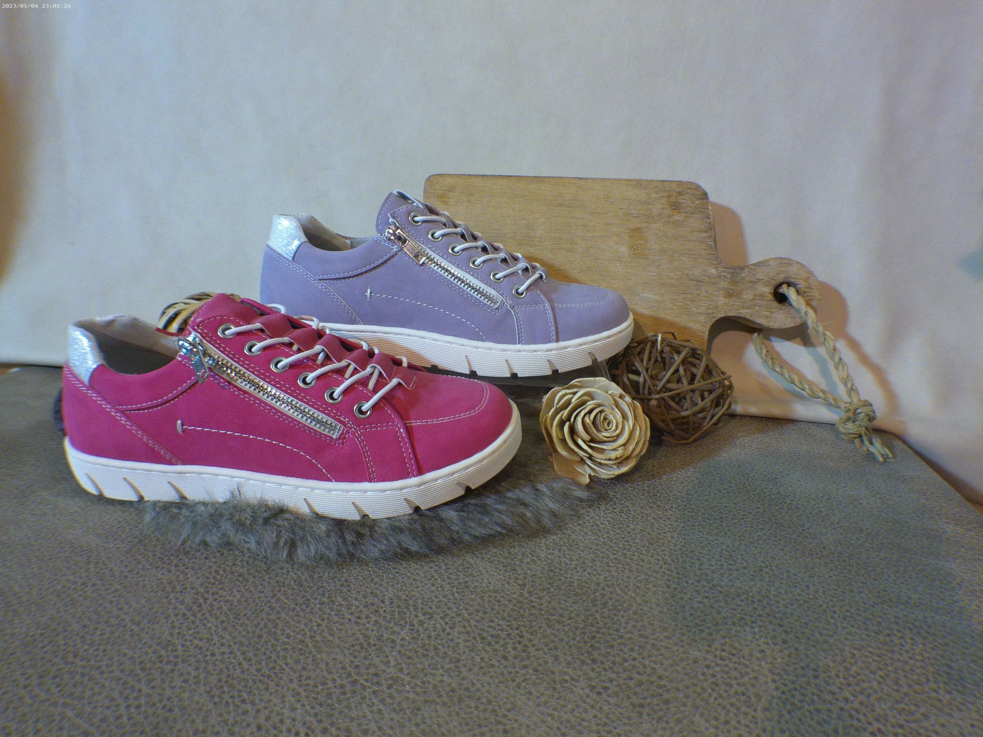 Een paar roze en paarse sneakers staan op een tafel.