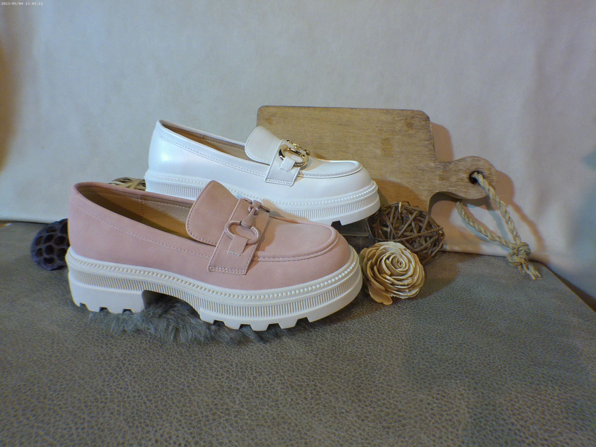 Een paar roze en witte loafers staan op een tafel.
