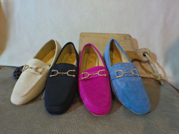Vier verschillend gekleurde loafers staan op een tafel opgesteld