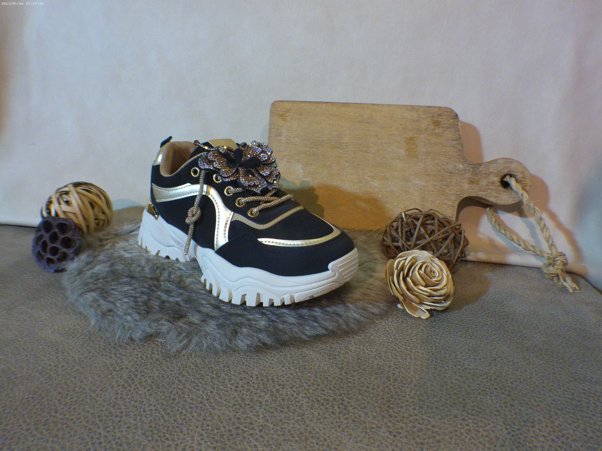 Een paar zwart-gouden sneakers liggen op een tapijt.
