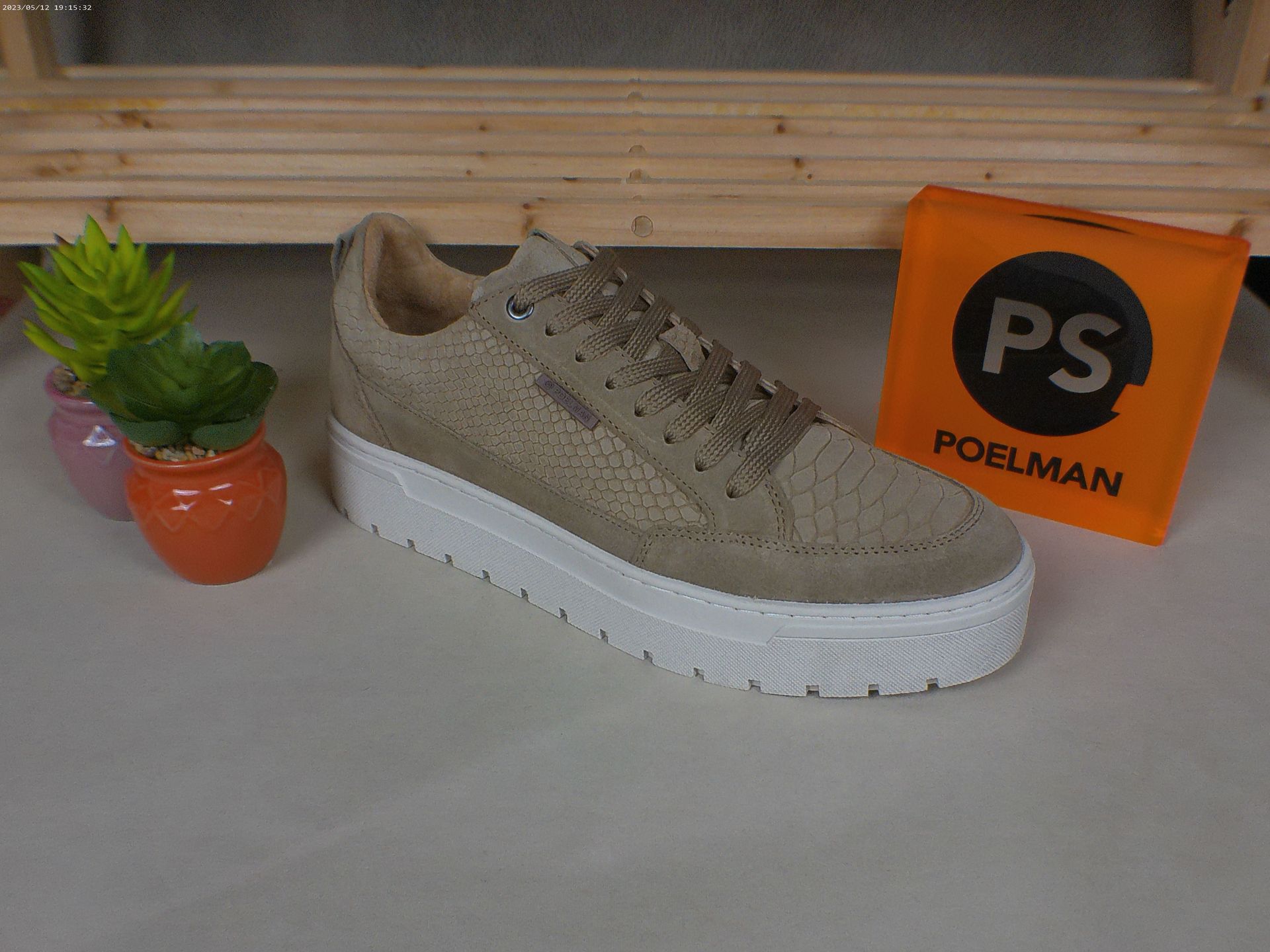 Een paar schoenen staat op een tafel naast een doos met de tekst ps.