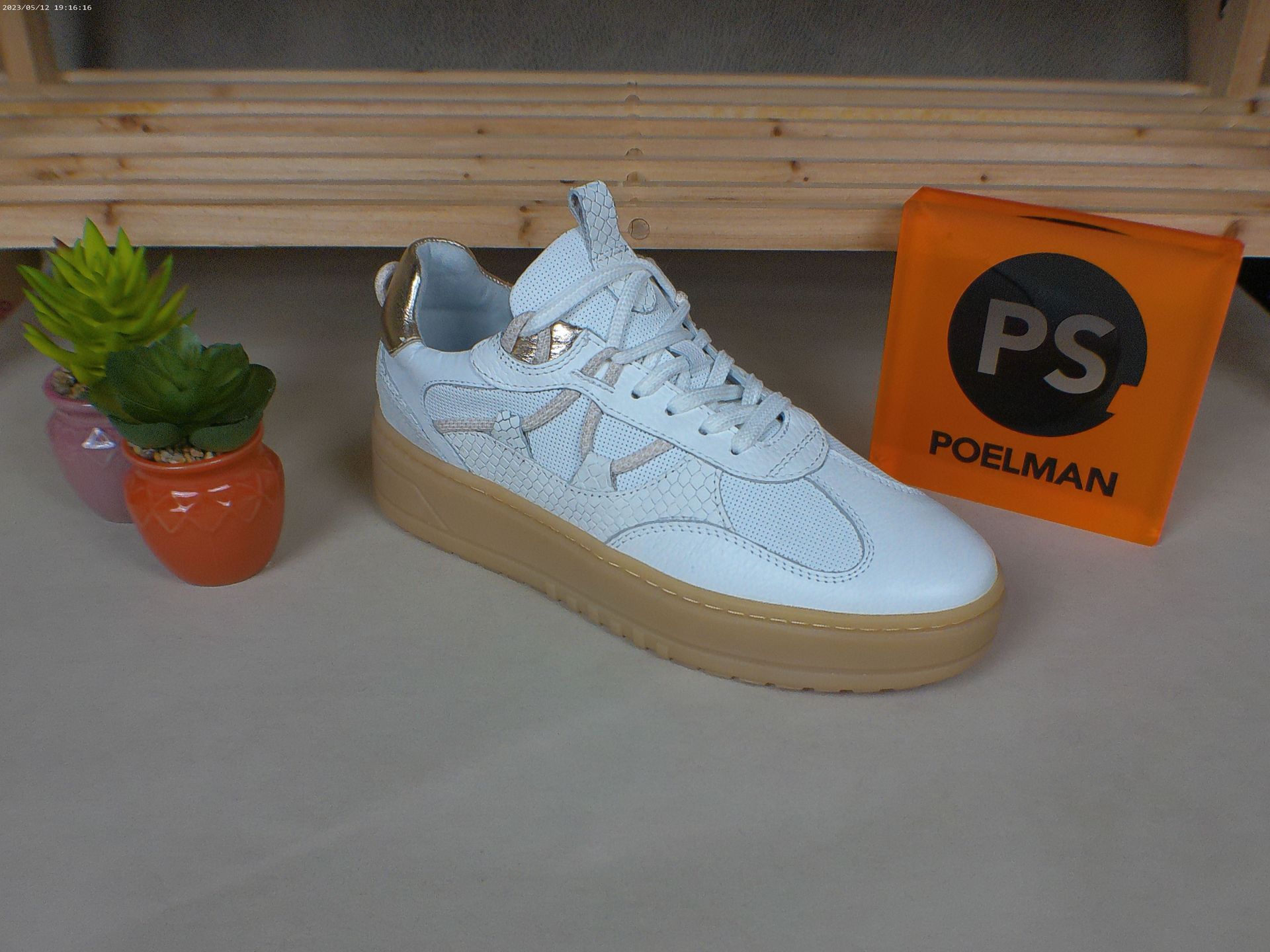 Een paar witte sneakers staan ​​op een tafel naast een potplant.