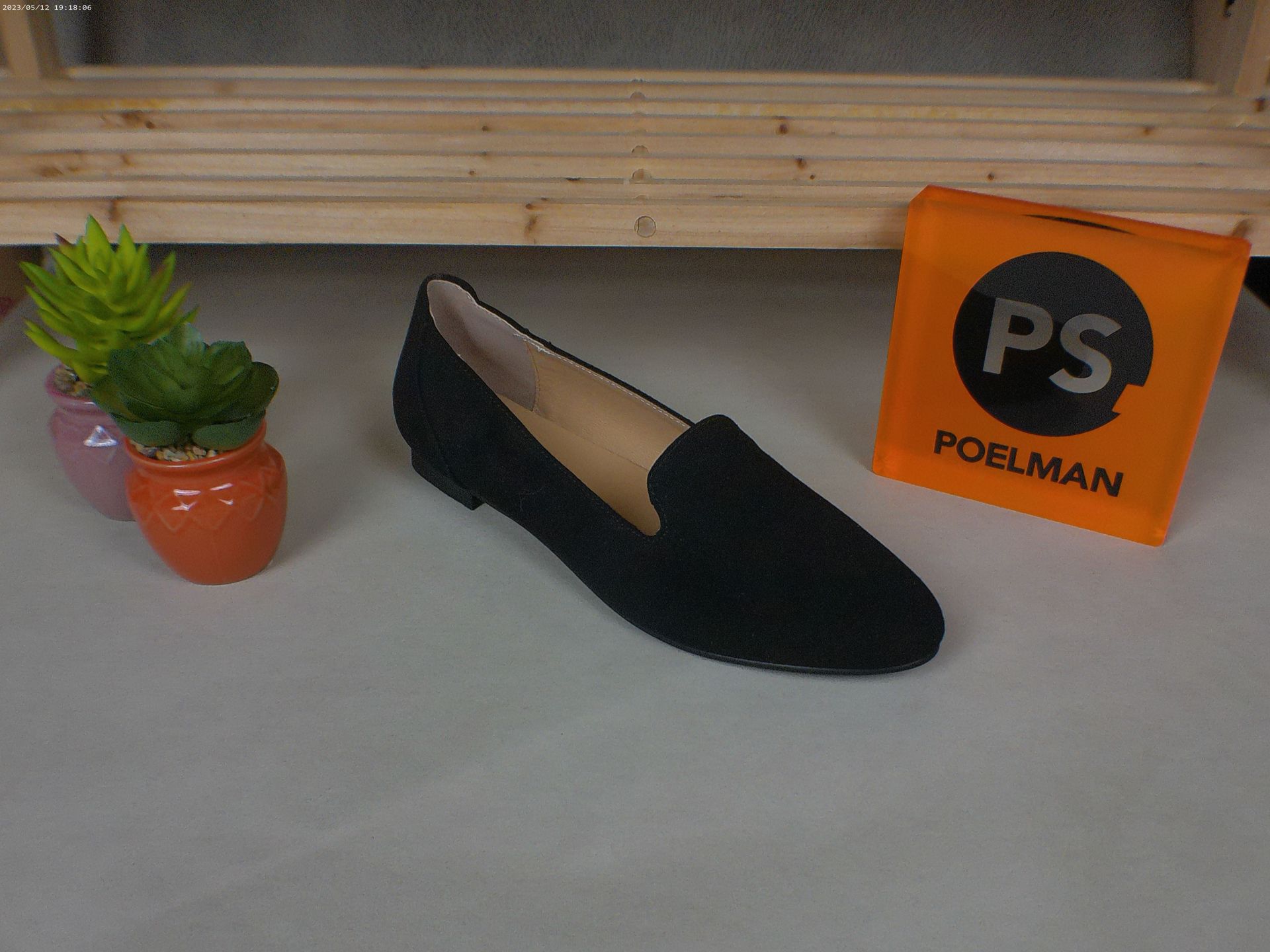 Een paar zwarte schoenen naast een oranje doos met de tekst ps
