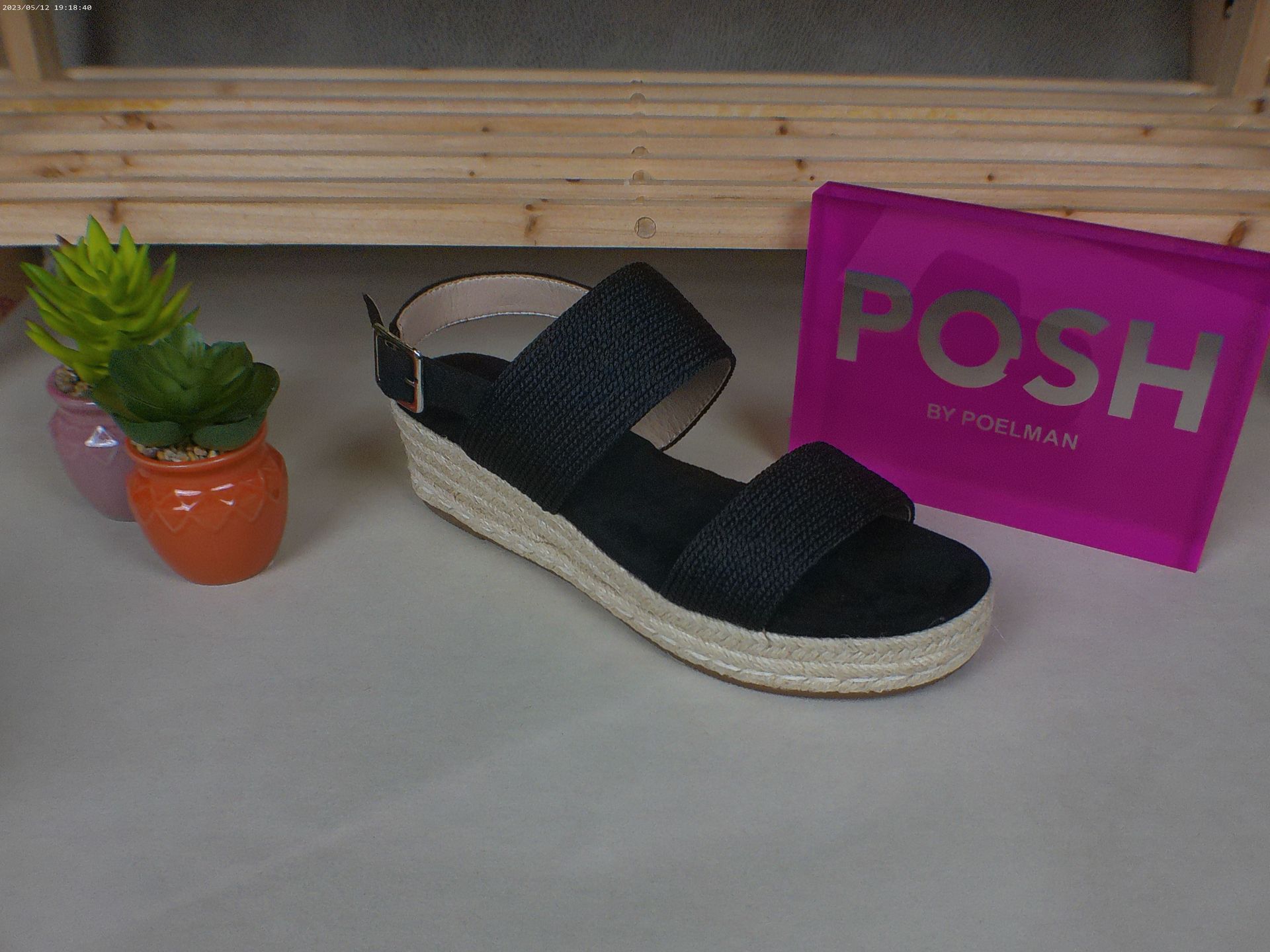 Een paar zwarte sandalen naast een chique roze tas