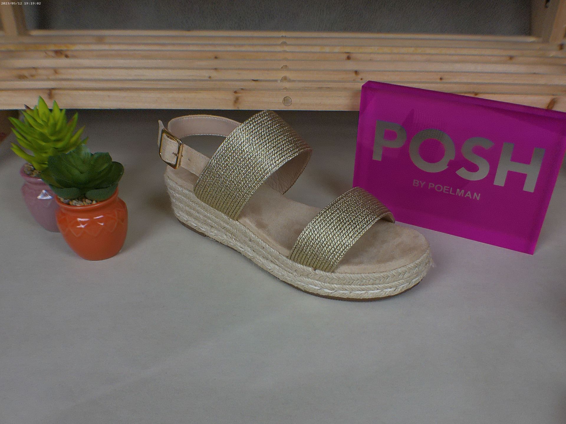 Een paar gouden sandalen staan ​​op een tafel naast een chique roze tas.