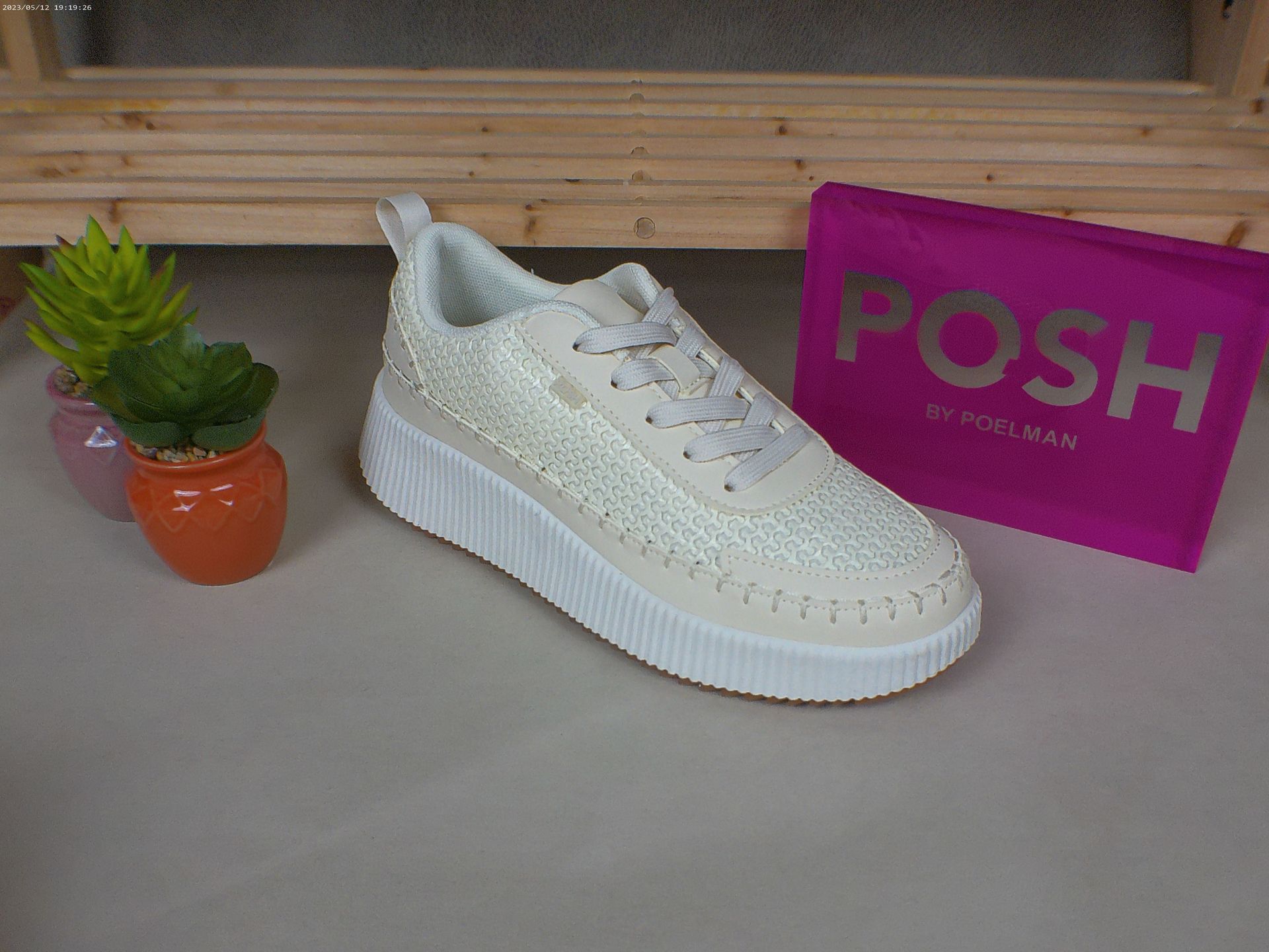 Een paar witte sneakers staan ​​op een tafel naast een chique roze tas.