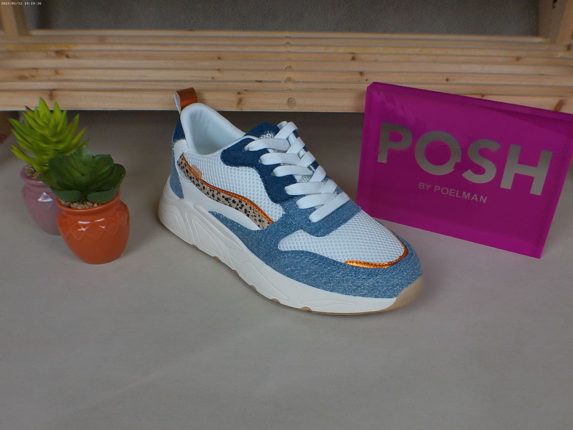 Een paar blauwe en witte sneakers naast een roze chique tas
