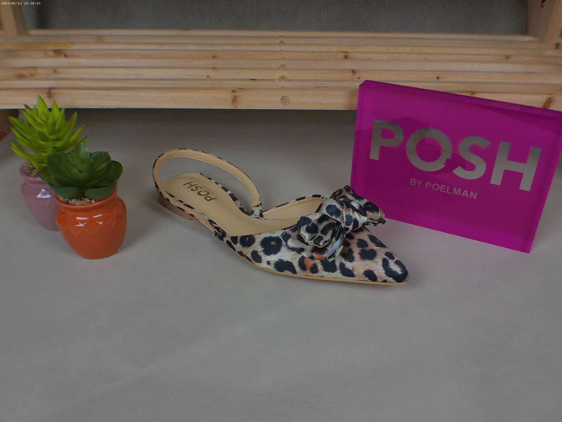 Een paar schoenen met luipaardprint naast een chique roze tas