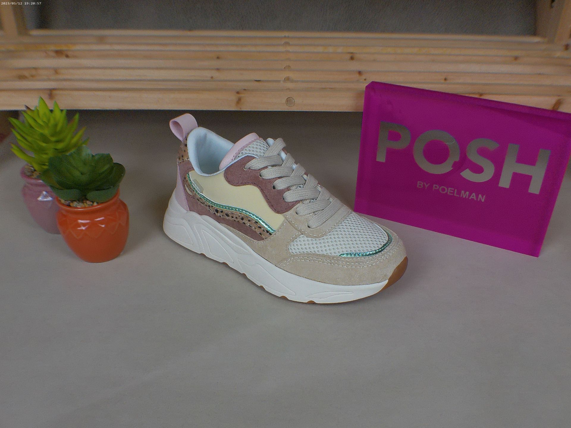 Een paar sneakers ligt op een tafel naast een chique roze tas.