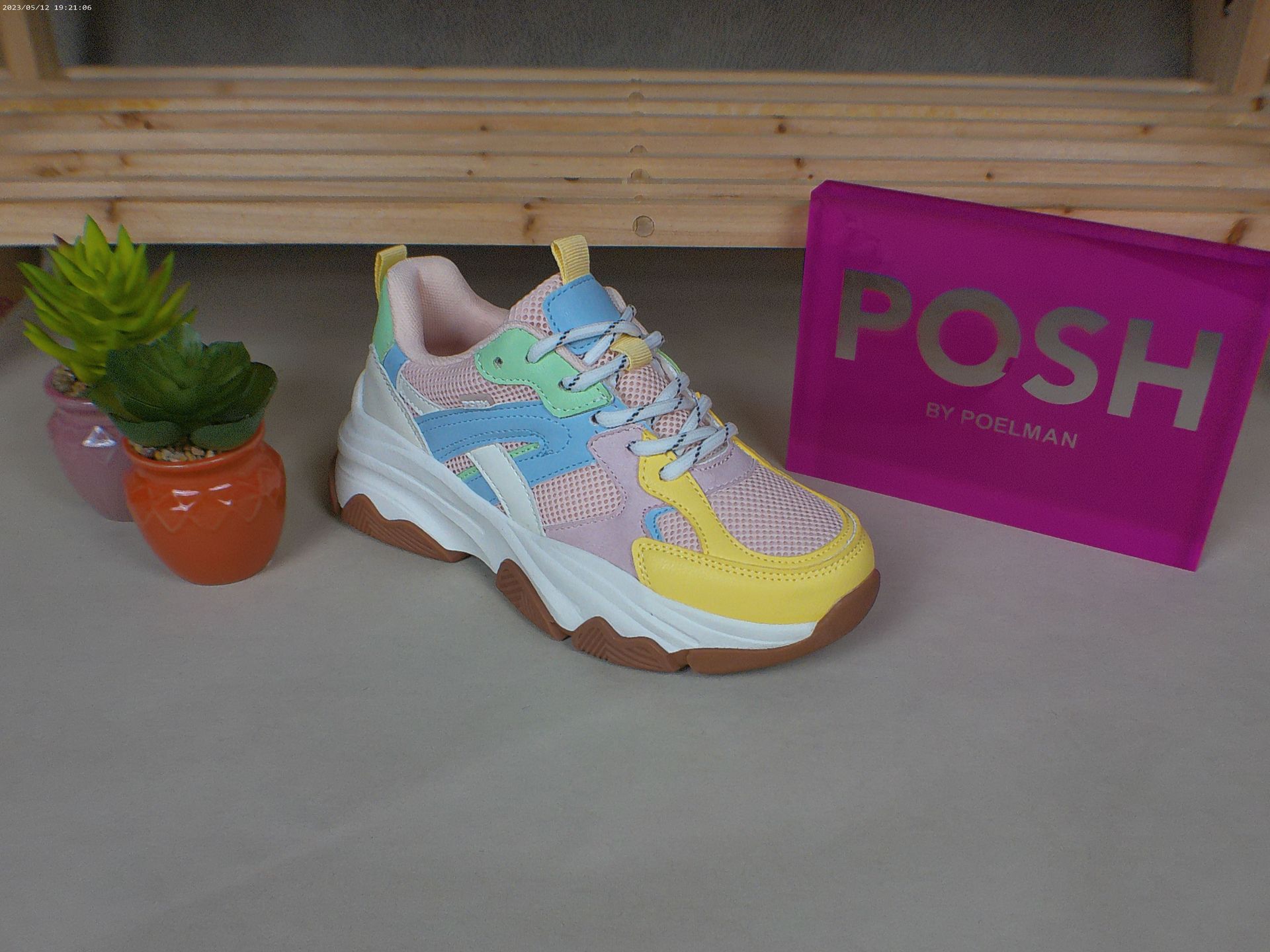 Een paar kleurrijke sneakers naast een roze chique tas