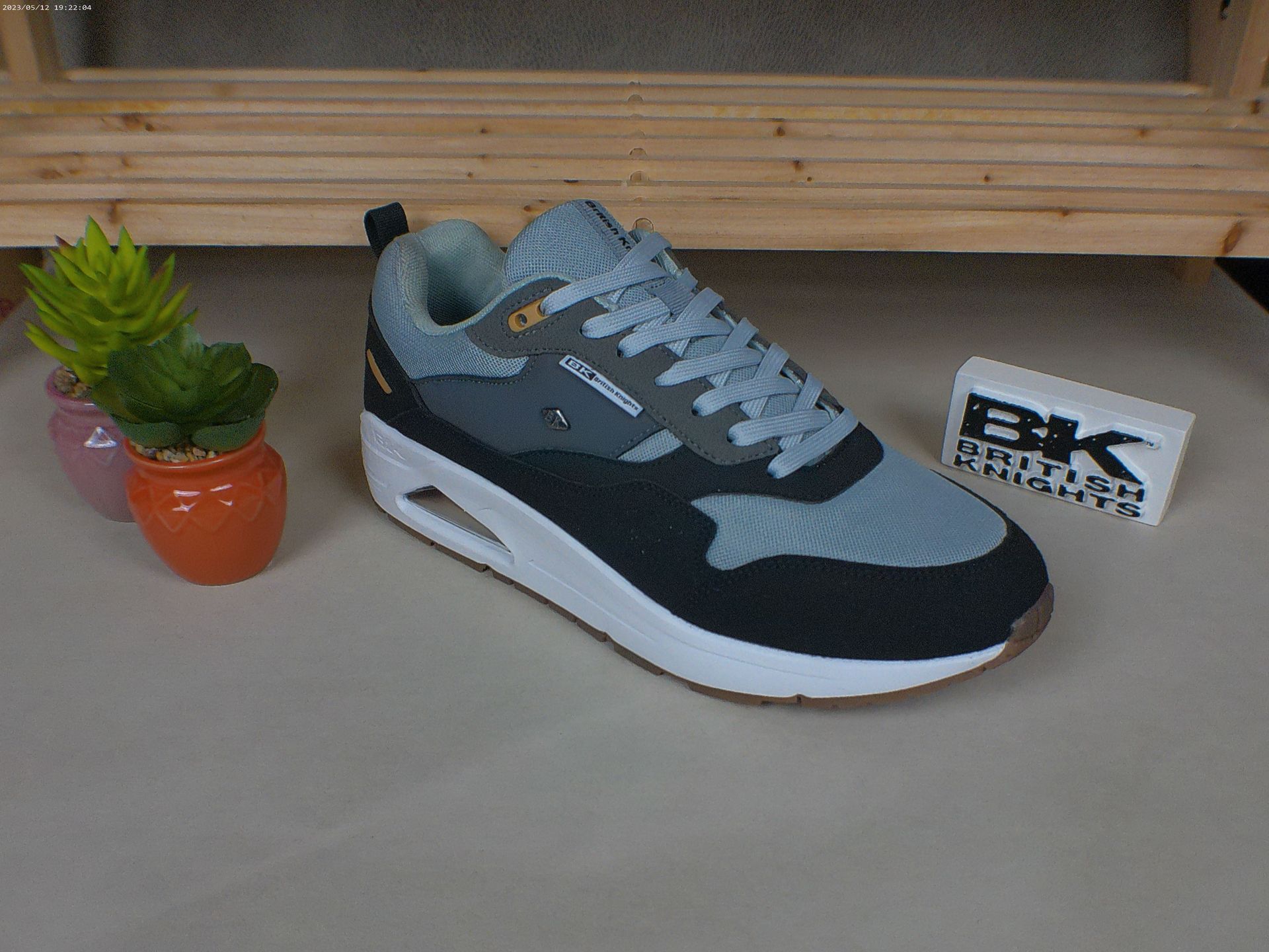 Een paar sneakers staat op een tafel naast een potplant.