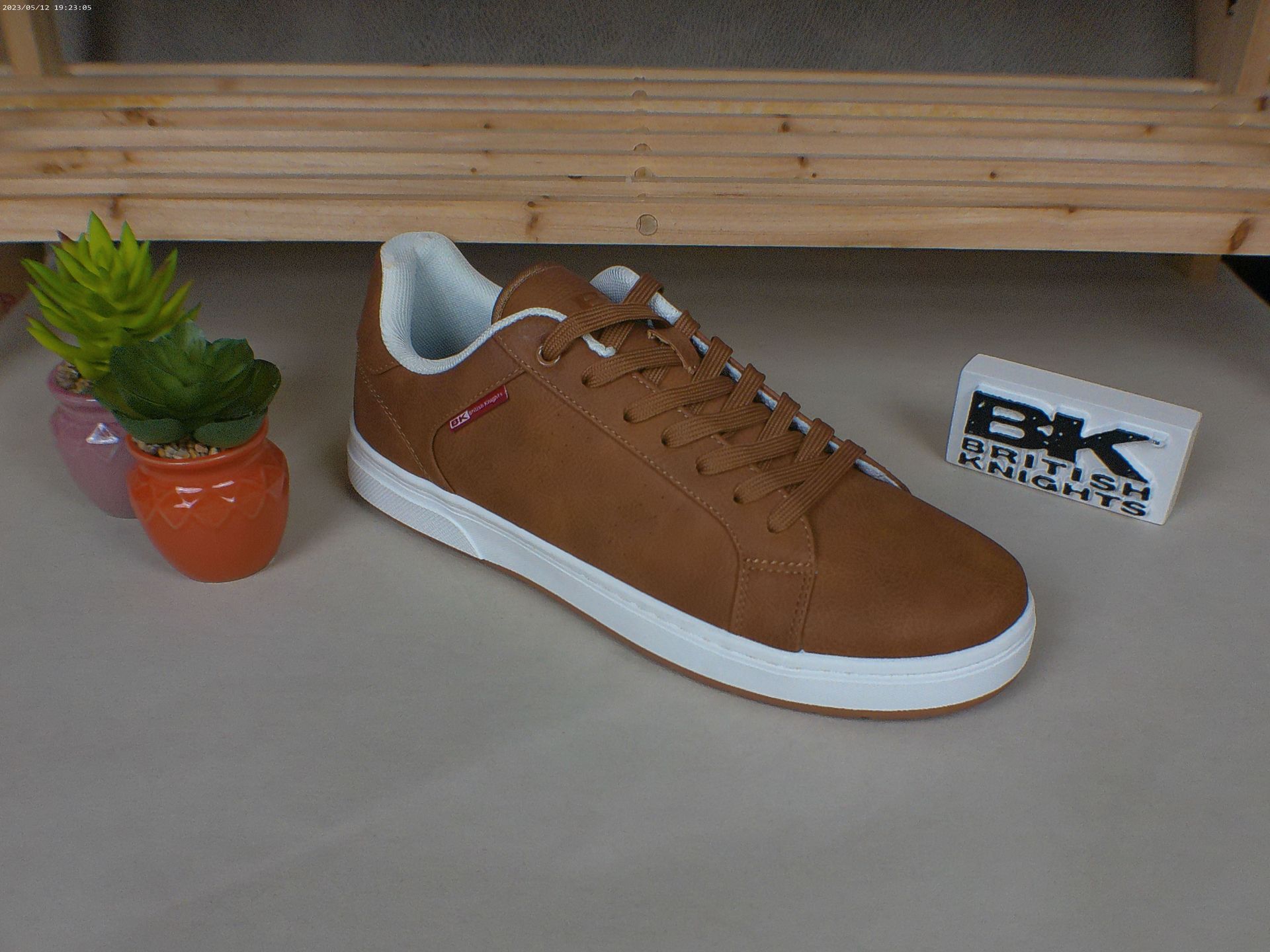 Een paar bruine sneakers staan ​​op een tafel naast een potplant.