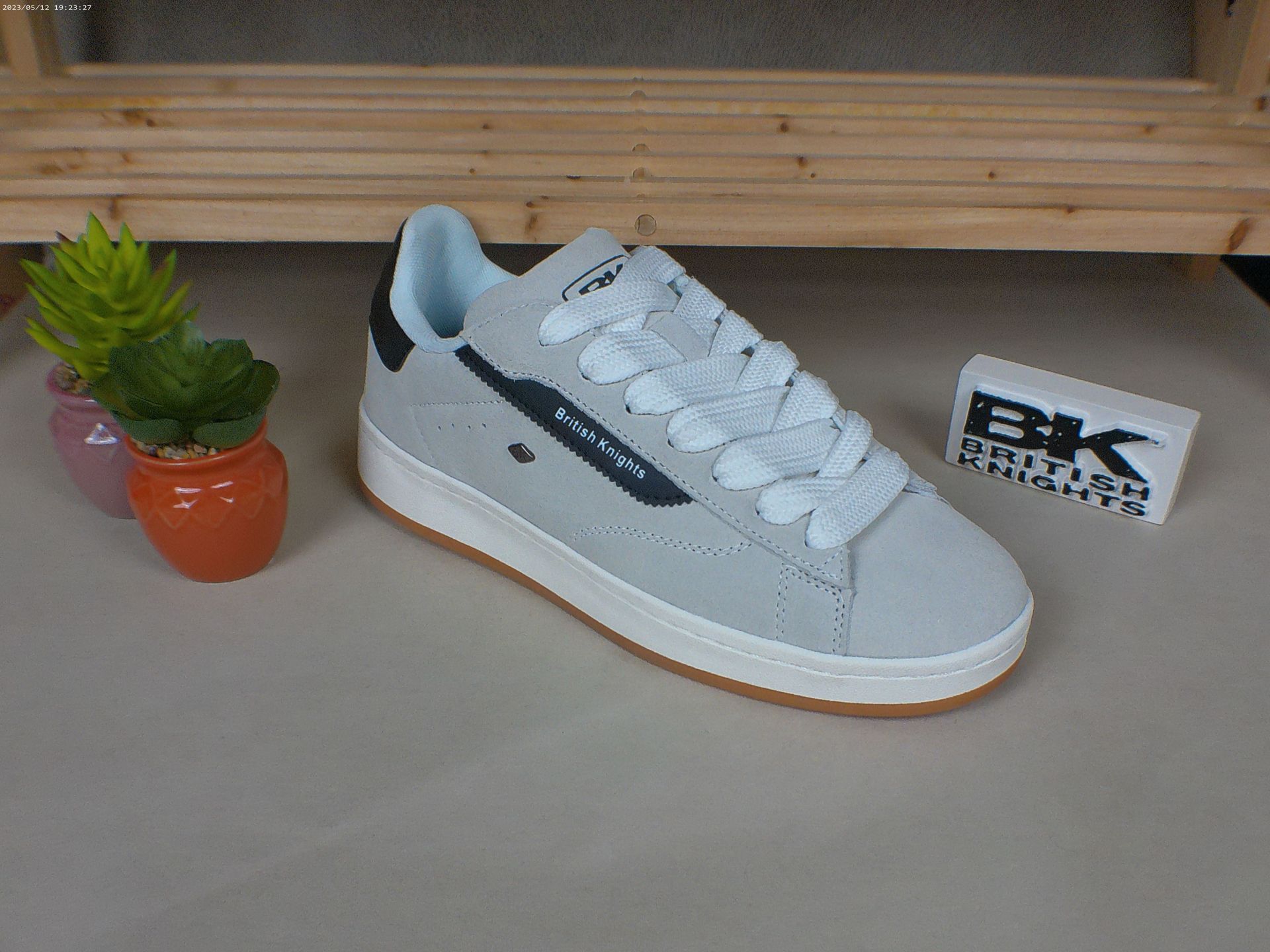 Een paar wit-blauwe sneakers staan ​​op een tafel naast een potplant.