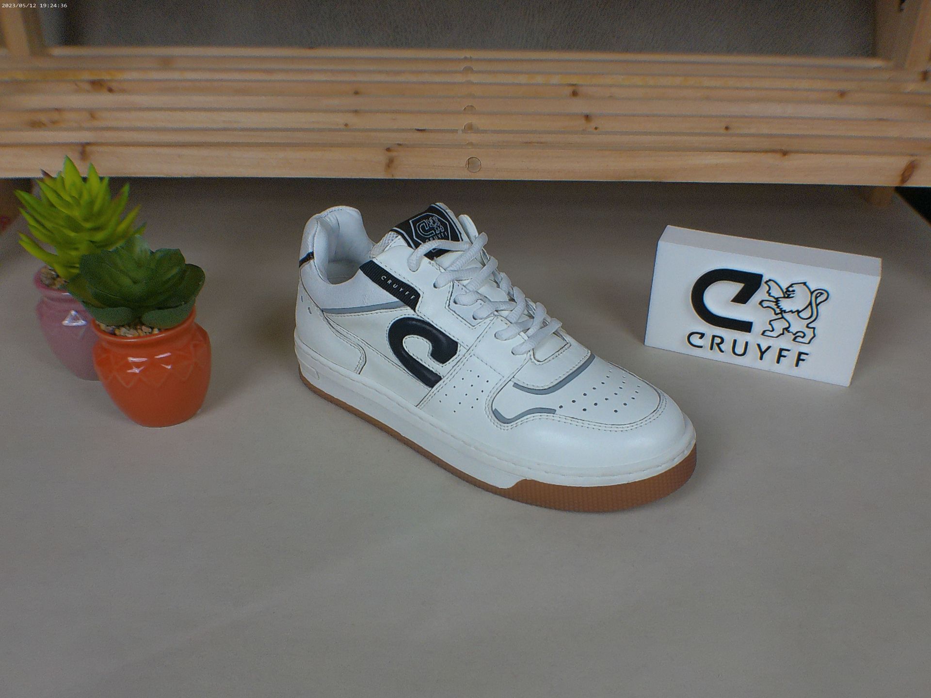 Een paar witte sneakers staan ​​op een tafel naast een potplant.