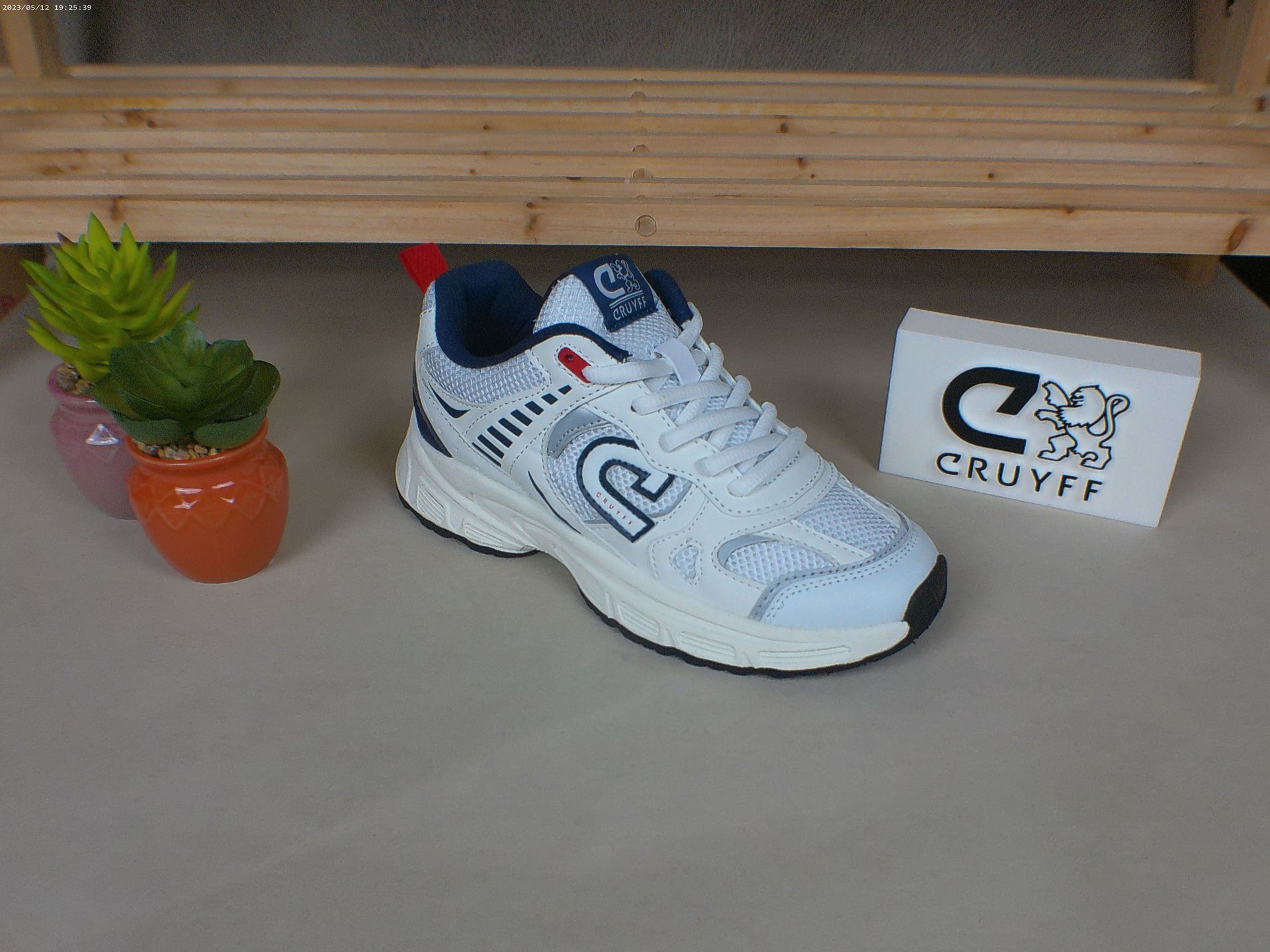 Een paar witte sneakers staan ​​op een tafel naast een potplant.