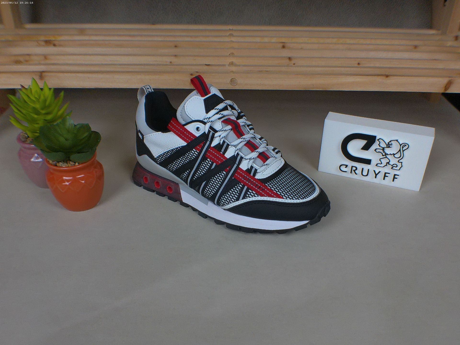 Een paar Cruyff-sneakers staan ​​op een tafel naast een potplant.