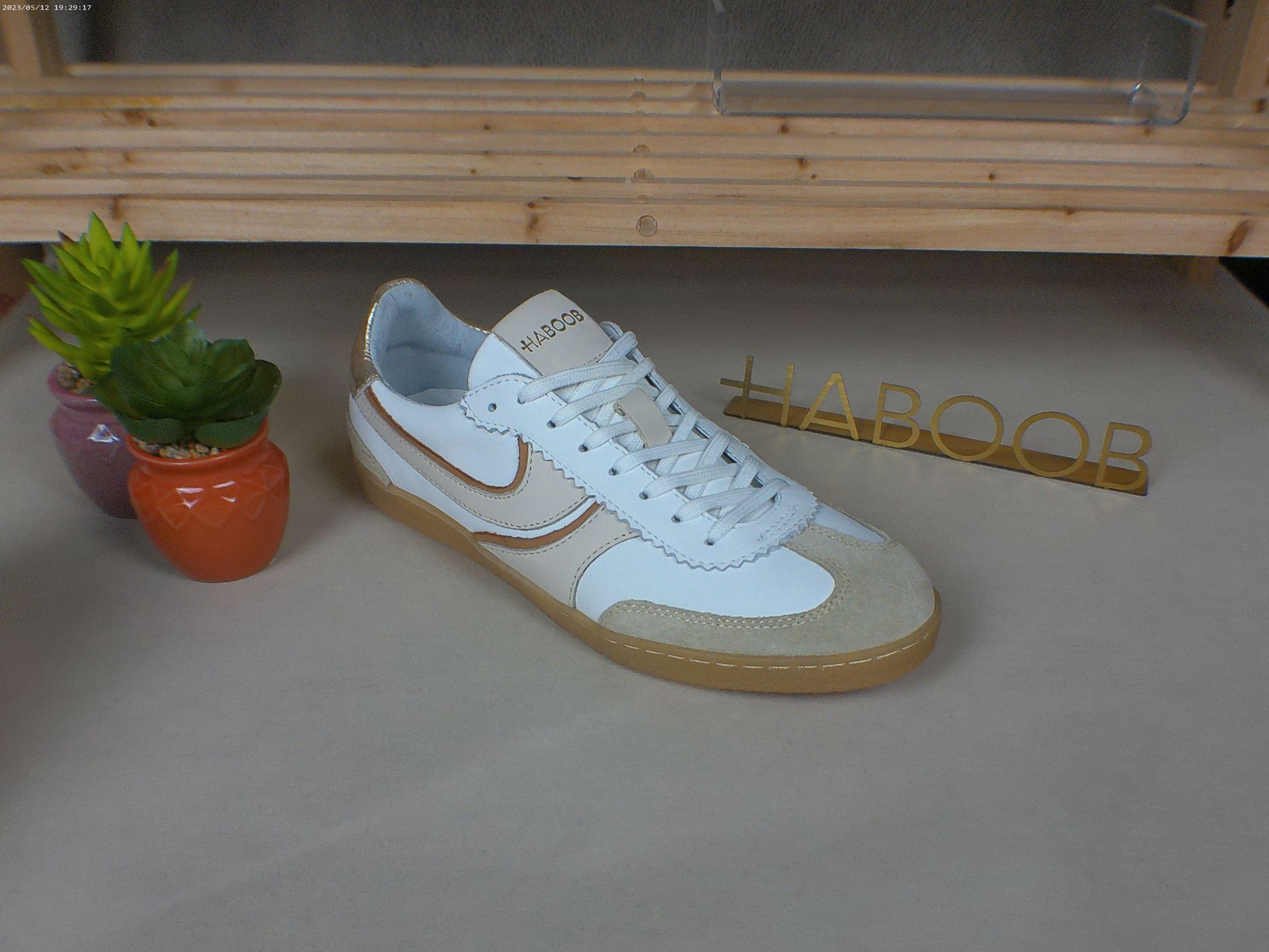 Een paar witte Nike-sneakers naast een potplant