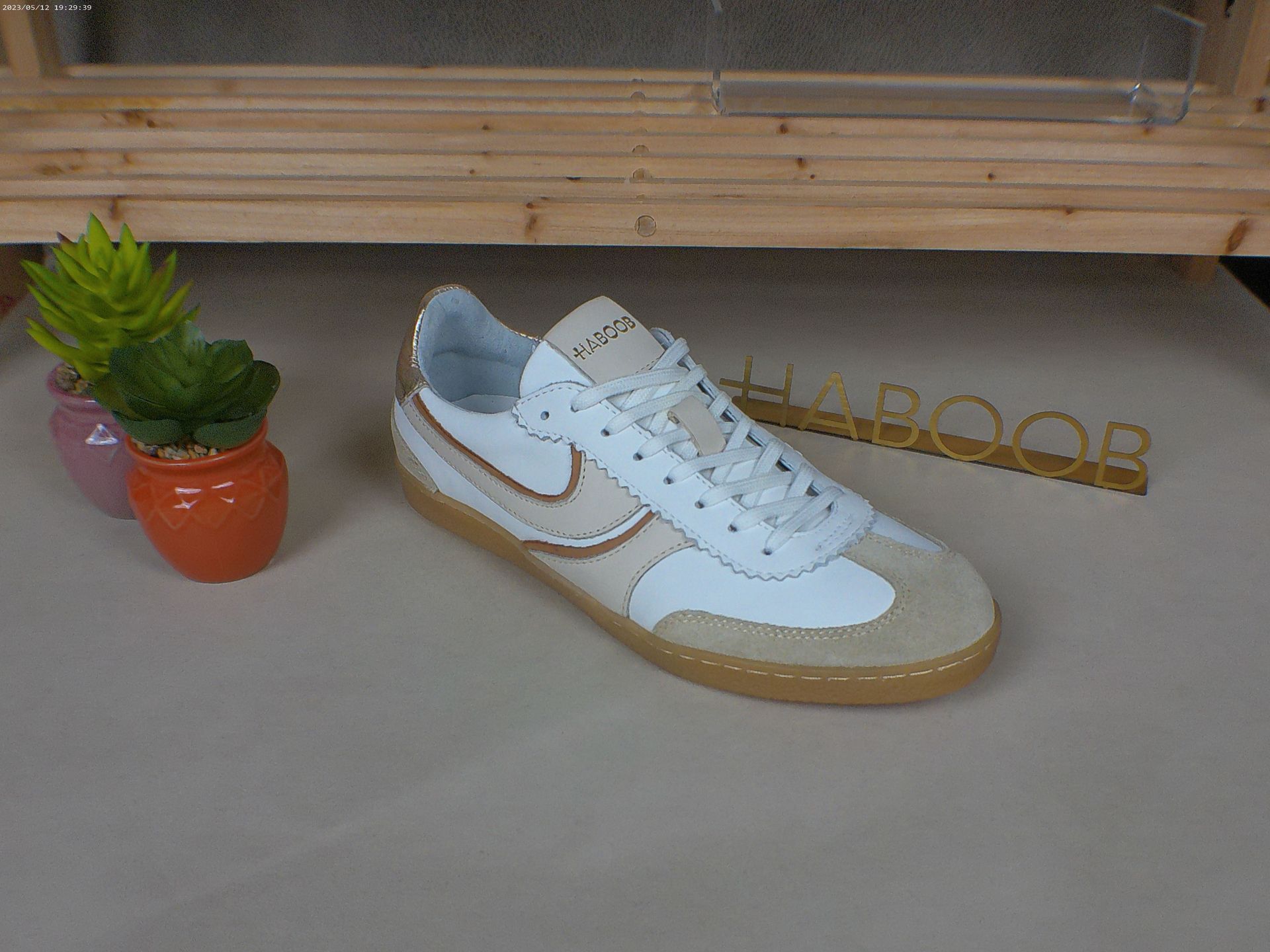 Een witte Nike-schoen staat op een tafel naast een potplant.