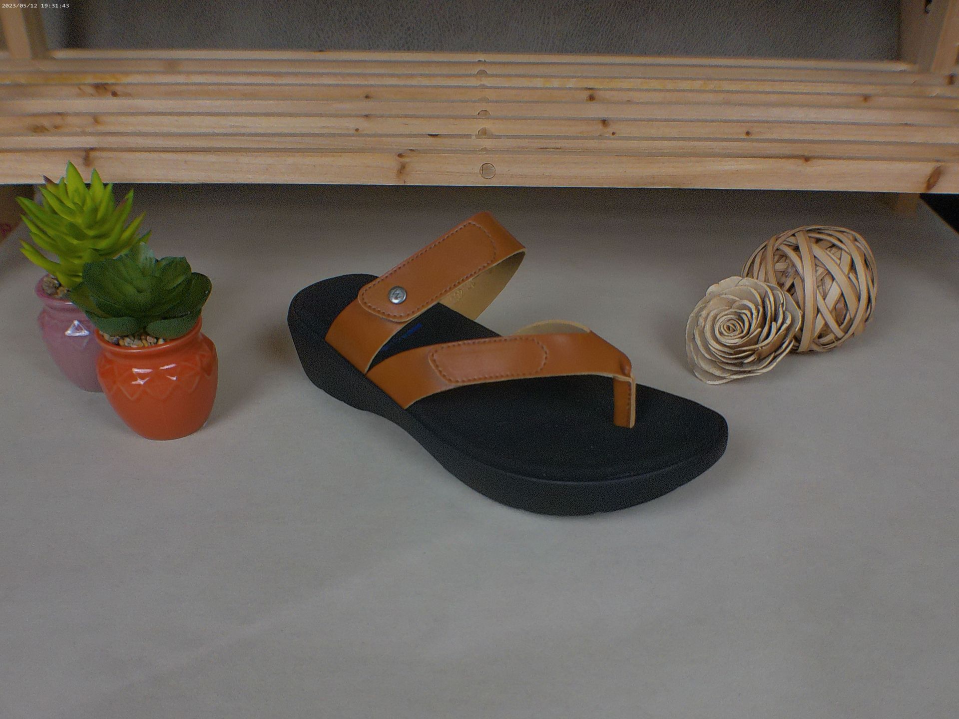 Een paar sandalen staat op een tafel naast een potplant.