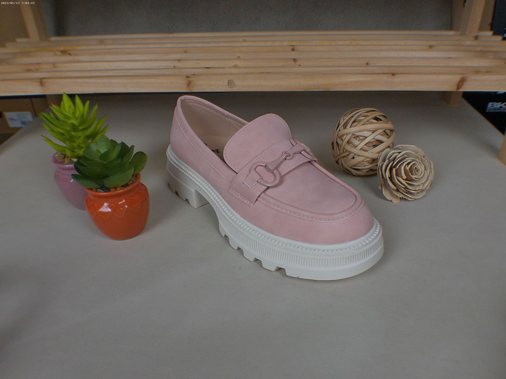 Een paar roze loafers staan ​​op een tafel naast een potplant.