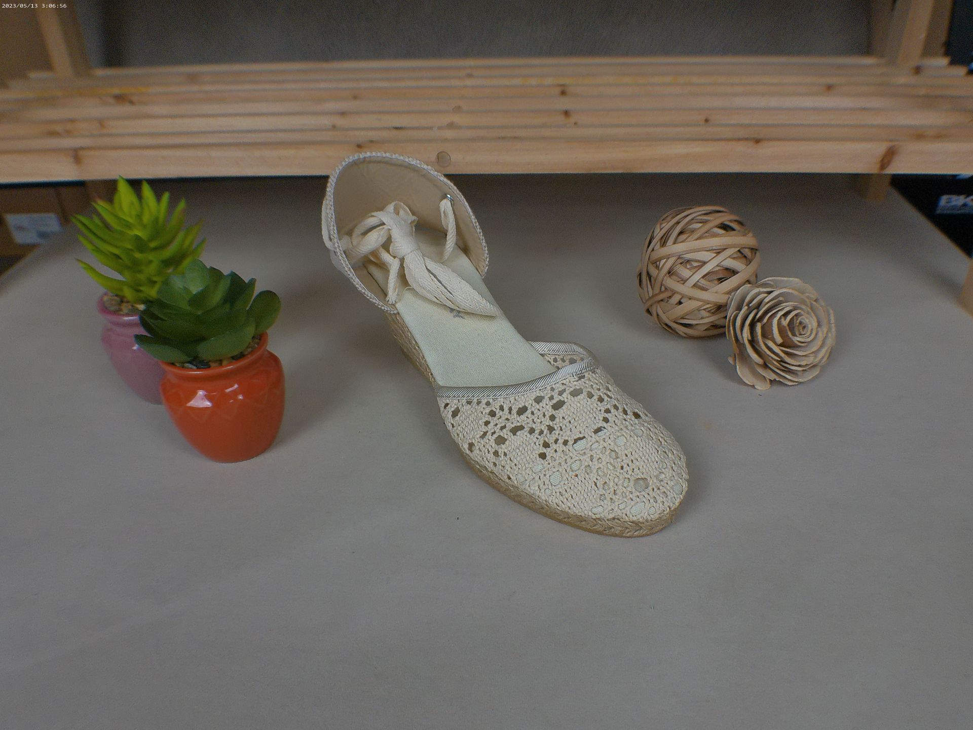 Een witte schoen staat op een tafel naast een potplant.