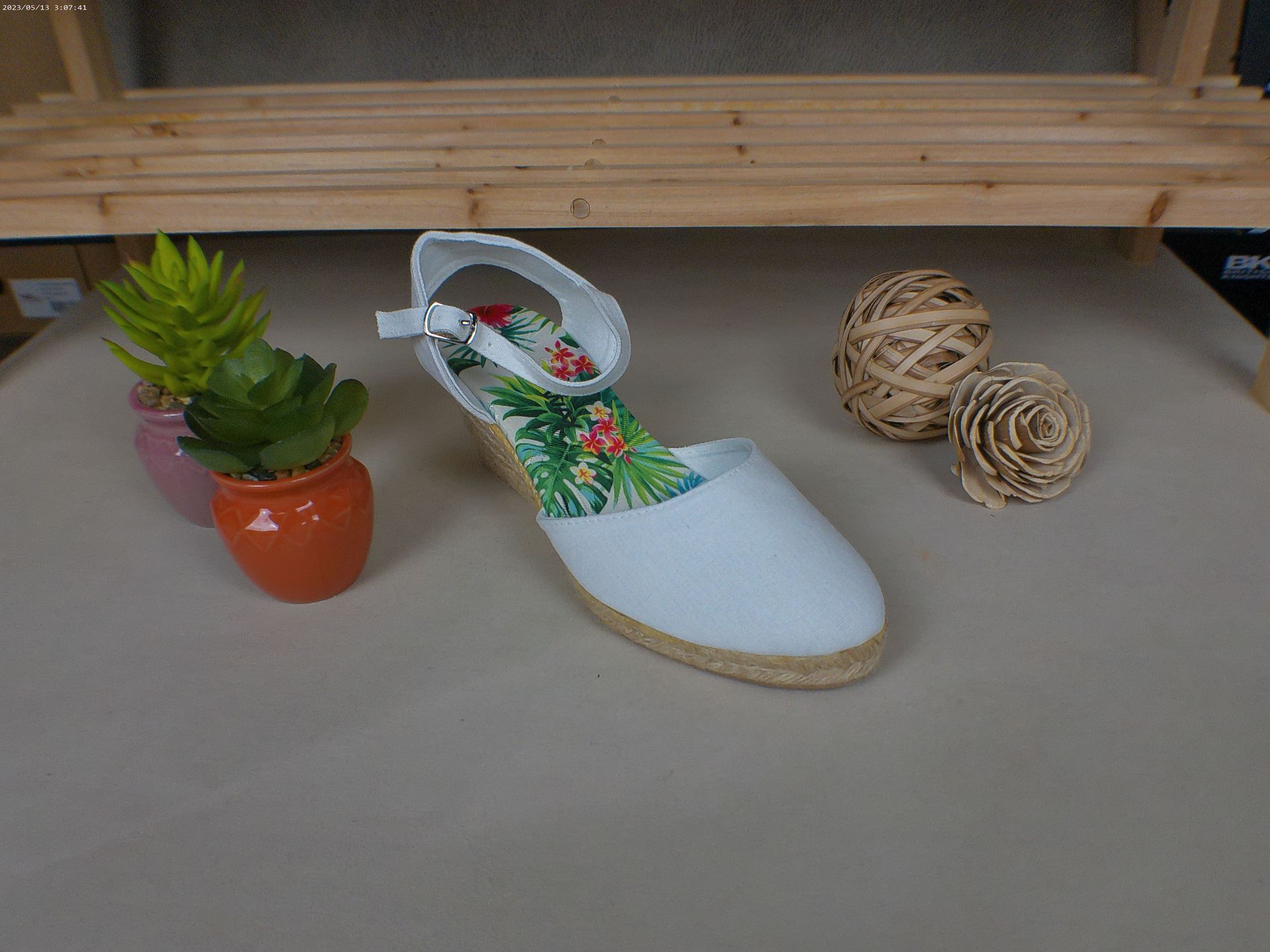 Een witte schoen staat op een tafel naast een potplant.