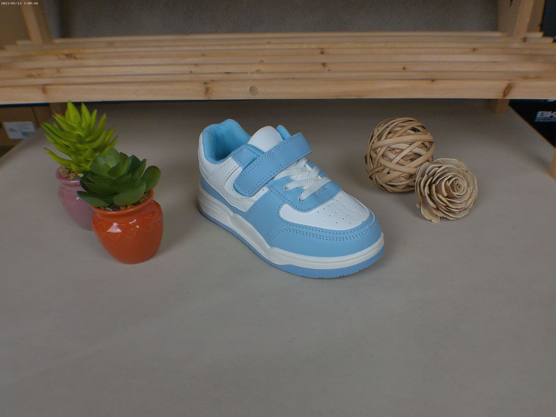 Een paar blauw-witte sneakers staan ​​op een tafel naast een potplant.