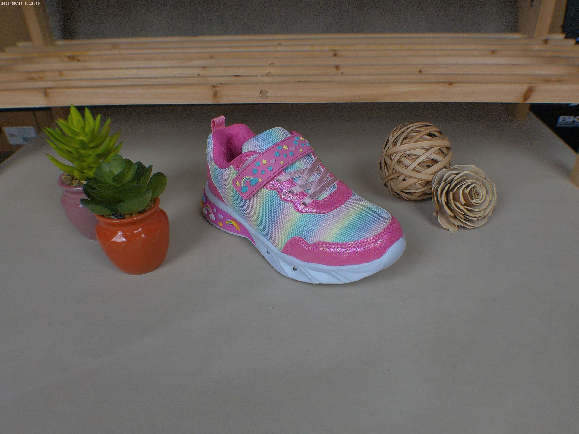 Een roze schoen staat op een tafel naast een potplant.