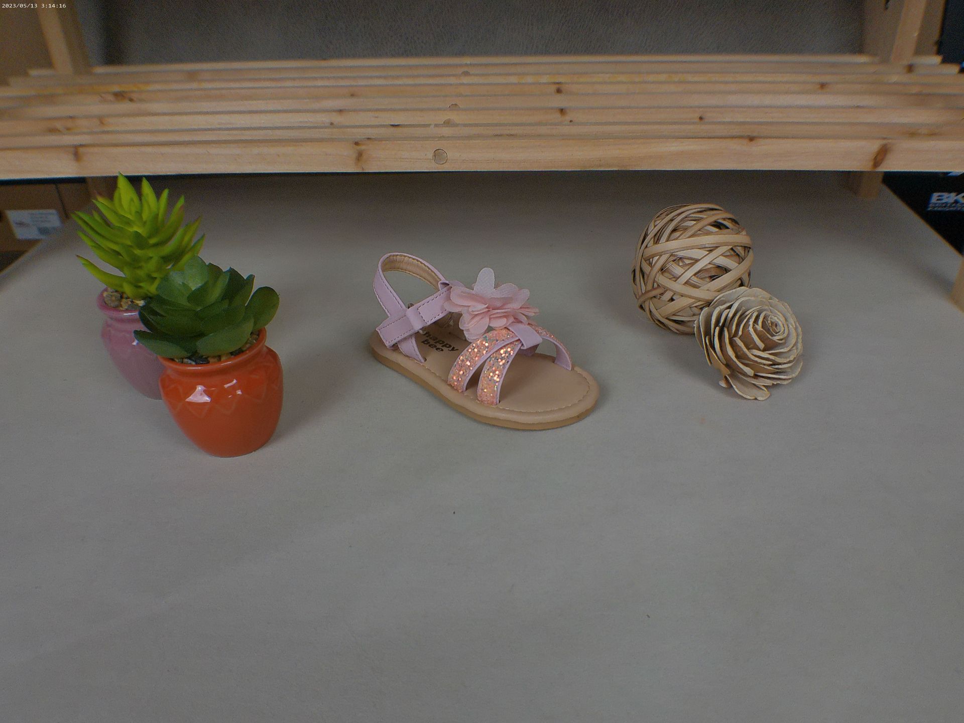Een paar roze sandalen staan ​​op een tafel naast een potplant.